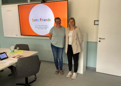 Fabienne Schnieder und Karen Gärtner stehen vor einem Bildschirm, Präsentation der Data Friends, Besprechungsraum