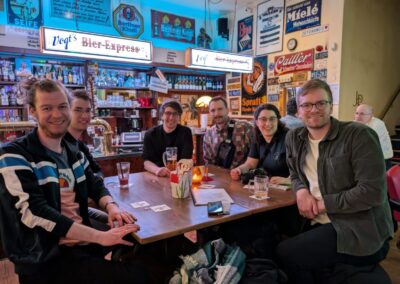 Statistiker aus Dortmund sitzen in einer Kneipe zusammen, im Hintergrund die Theke mit zahlreichen Bierwerbungen