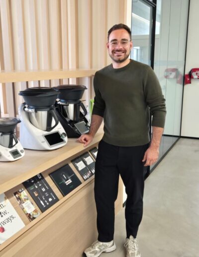 Leif Struwe, Mann mit Brille in grünem Pullover, steht neben unterschiedlichen Versionen des Thermomix, Vorwerk Home & Co. KmG in der Schweiz