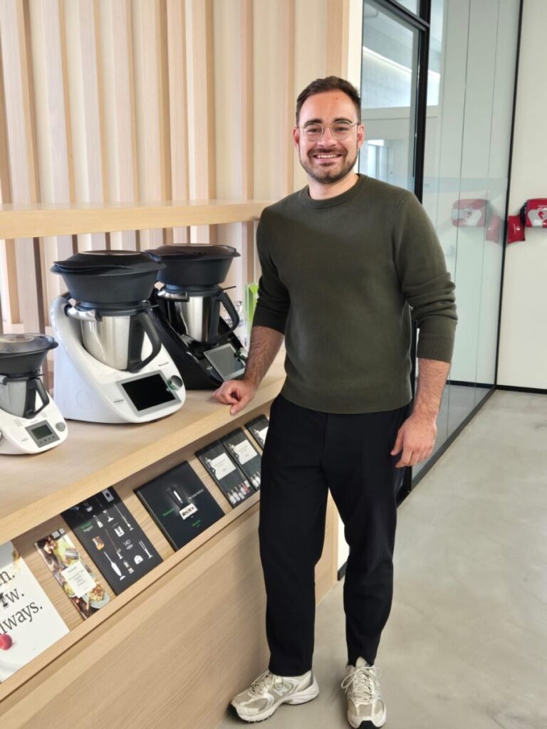Leif Struwe, Mann mit Brille in grünem Pullover, steht neben unterschiedlichen Versionen des Thermomix, Vorwerk Home & Co. KmG in der Schweiz