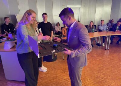 Lara Kuhlmann hält einen gebastelten Doktorhut und Dr.-Ing. Maximilian Kiefer betrachtet den Hut