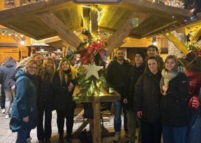 Eine Gruppe von Menschen steht an einem Tisch auf dem Weihnachtsmarkt in Dortmund, Holzdach, Weihnachtsdekoration