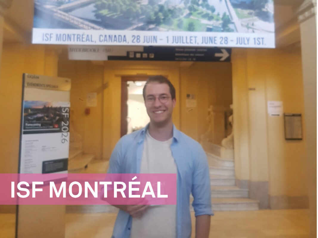 erfahrungsbericht-jakob-becker-montreal Jakob Becker, Mann mit braunen, kurzen Haaren, steht in einem Flur, Wände holzvertäfelt, Treppenaufgang, Banner der ISF Montreal