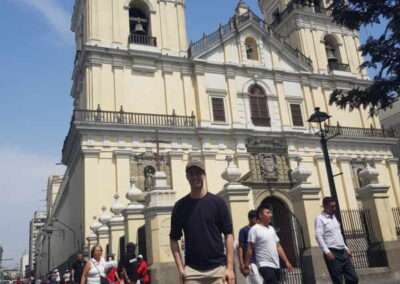 Kirche in Lima, Jakob Becker steht davor, Menschen laufen über den Kirchhof